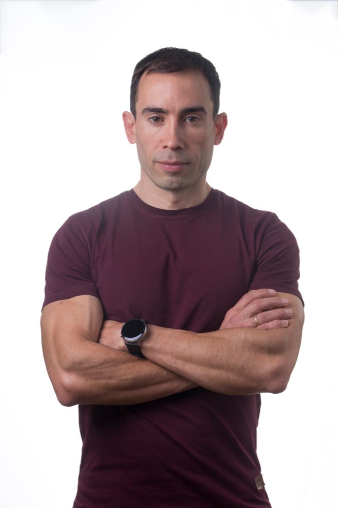 Retrato de Marcos Vázquez, de brazos cruzados, con camiseta granate